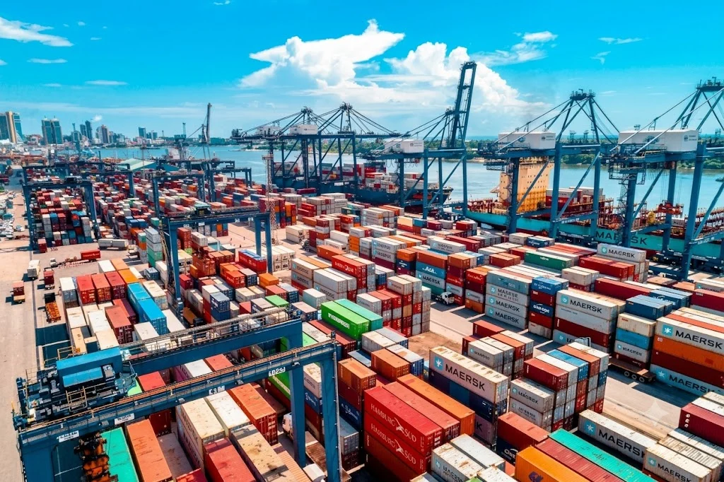 Container terminal with stacked shipping containers and quay cranes on a sunny day